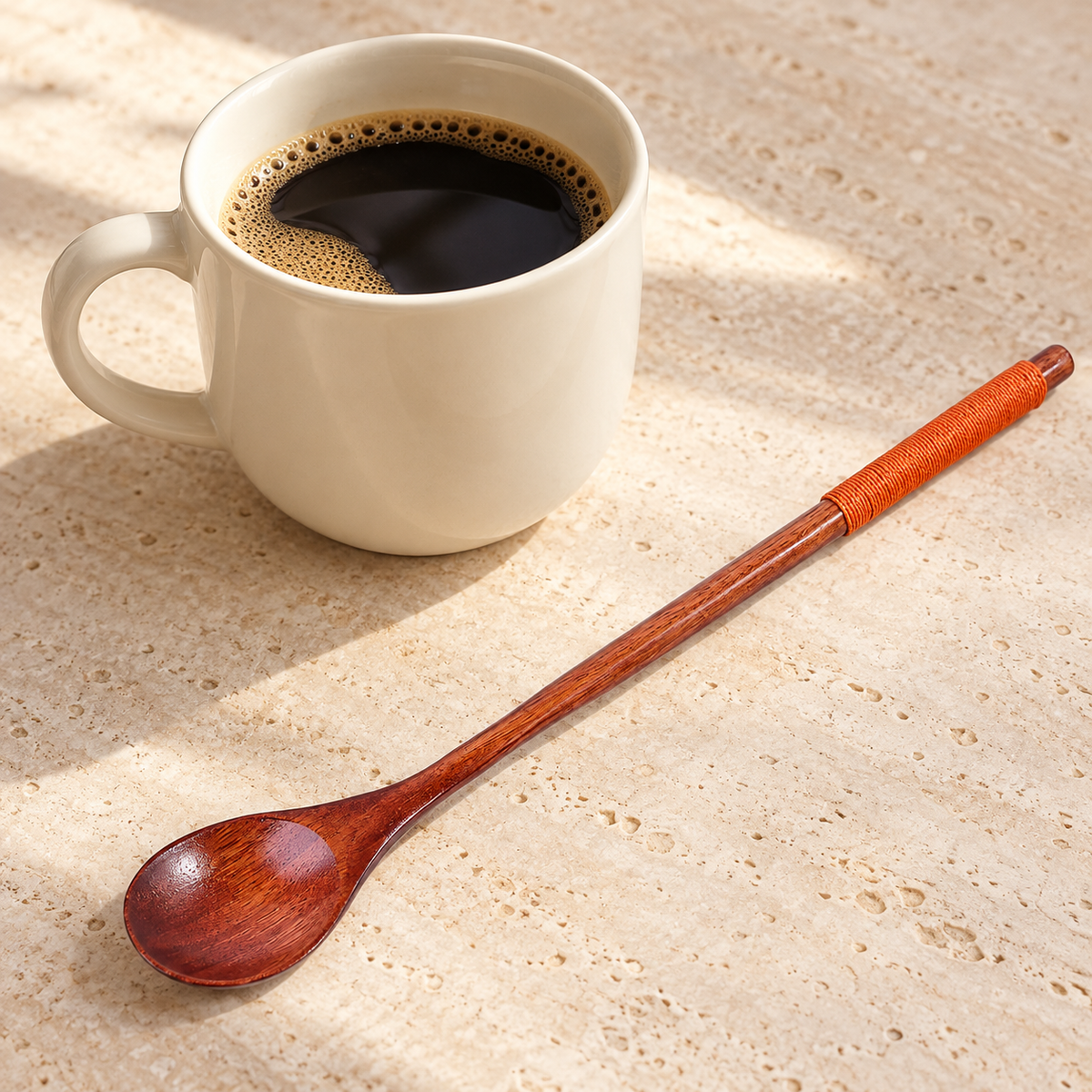 LöffelKlar – einzelner brauner Löffel mit orangefarbenem Griffband neben Kaffee